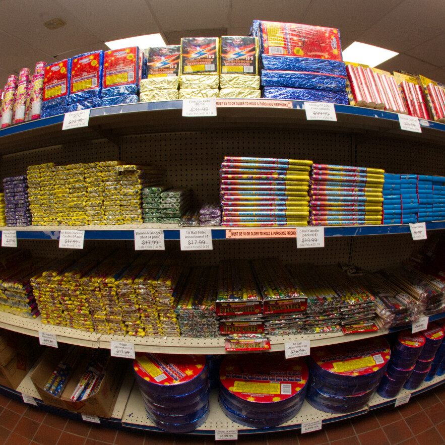 Shelves stocked with various firework assortments and prices displayed.